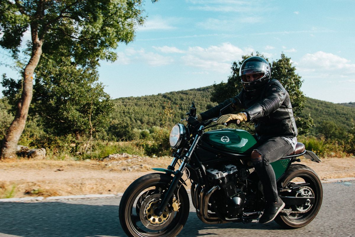 Motard équipé, casque et blouson, sur une route ensoleillée
